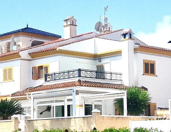 Weiß verputztes Eckreihenhaus mit Balkon, Markise und verglaster Veranda