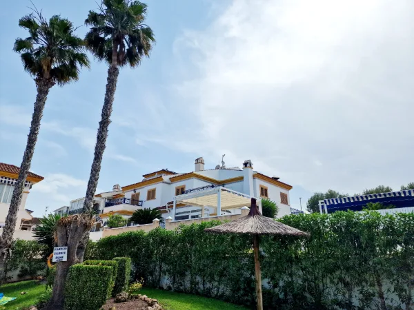 Weiß verputztes Eckreihenhaus mit Balkon, Markise und verglaster Veranda
