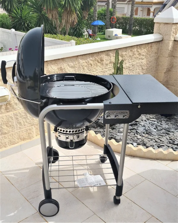 Schwarzer Kugelgrill auf gefliester Terrasse