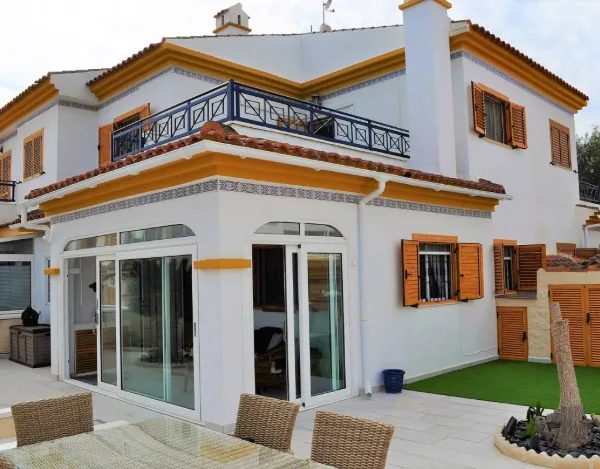 Hausfront mit gelben Fensterrahmen und möblierter Terrasse davor